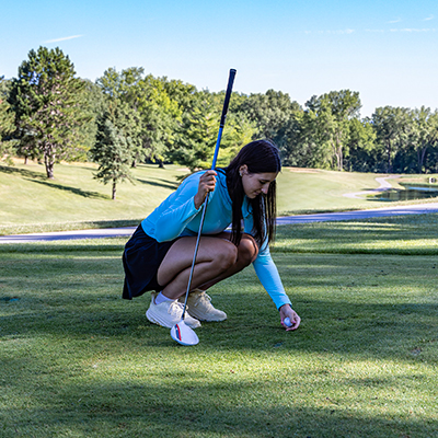 Woman golfer setting ball on tee at tee box